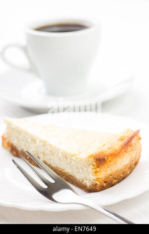 Keil Käsekuchen mit Kaffee und Dessertgabel. Restaurant Frühstück Hintergrund Stockfoto