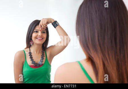 Junge Frau, die sich selbst im Spiegel betrachten Stockfoto