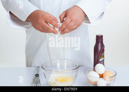 Küchenchef knacken Ei in Schüssel Stockfoto