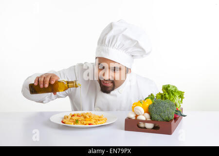 Küchenchef gießt Olivenöl auf pasta Stockfoto