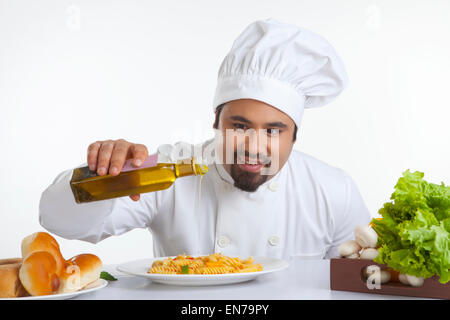 Küchenchef gießt Olivenöl auf pasta Stockfoto