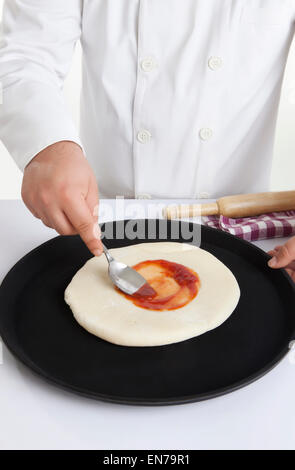 Koch Anwendung Belag auf Pizzateig Stockfoto