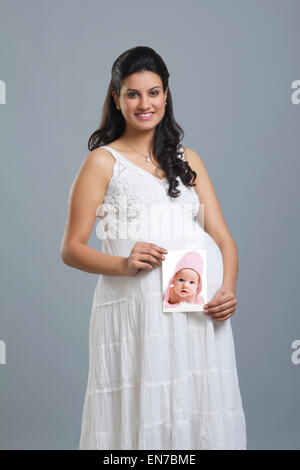 Porträt einer schwangeren Frau hält ein Bild eines Babys Stockfoto