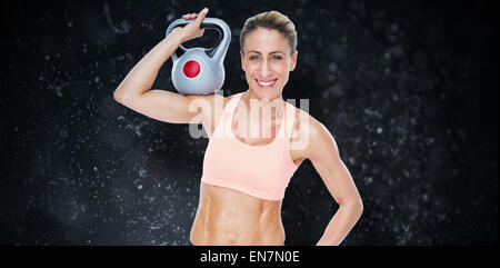 Zusammengesetztes Bild des weiblichen blonde Crossfitter Kettlebell lächelnd in die Kamera halten Stockfoto