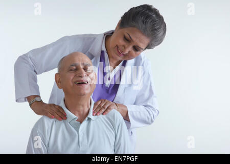 Arzt massieren alten mans Schultern Stockfoto