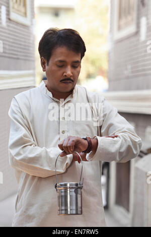 Mann hält Milch Kanister und Blick auf Uhr Stockfoto