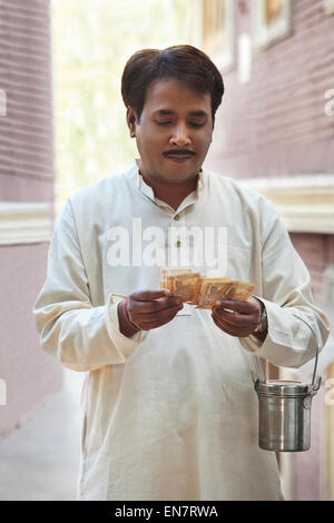 Mann hält Milch Kanister und zählen Rupien Stockfoto