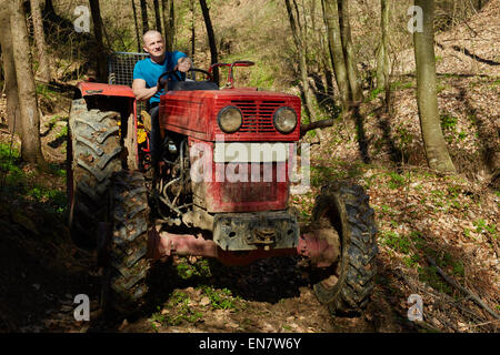 Junge kaukasischen Holzfäller seine Protokollierung Traktor zu fahren, um den richtigen Ort im Wald Stockfoto