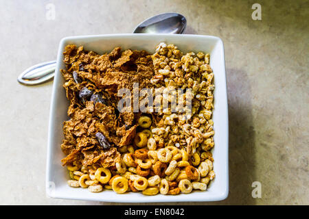 Cheerio's, Kashi Go Lean Crunch und Shop Marke Rosine Kleie Getreide in eine quadratische Schüssel zum Frühstück. Stockfoto