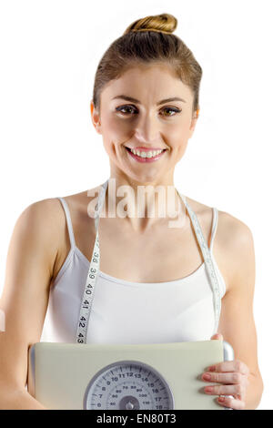 Schlanke Frau hält Waage und Maßband Stockfoto