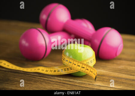 Rosa Hanteln mit grünem Apfel und Maßband Stockfoto