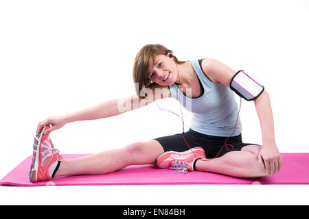 Hübsche Brünette tun die Kniesehne Strecke auf Gymnastikmatte Stockfoto