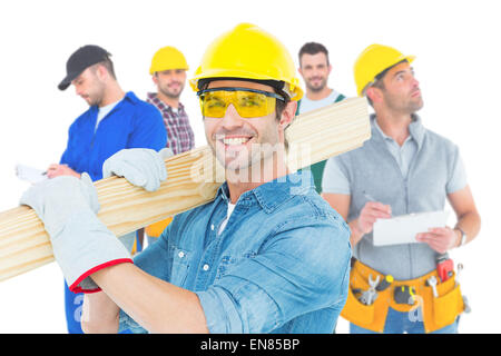 Zusammengesetztes Bild von Carpenter tragen Helm und Brille während des Tragens Holzbohlen Stockfoto