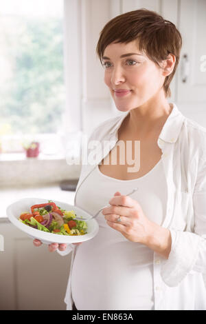 Schwangere Frau, die Schüssel Salat Stockfoto