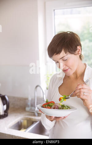 Schwangere Frau, die Schüssel Salat Stockfoto