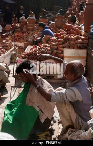 Ein Barbier bei der Arbeit neben einem Terrakotta-Geschäft in Kathmandu. Stockfoto