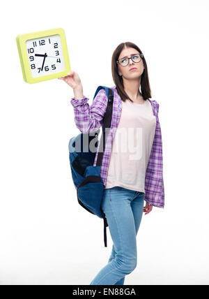 Traurig Studentin mit Blick auf die große Uhr über weißem Hintergrund Rucksack Stockfoto