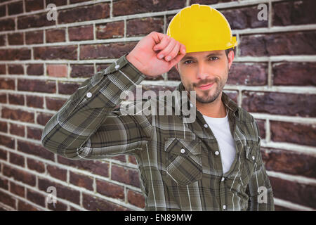 Zusammengesetztes Bild des Lächelns Handyman Holding Helm Stockfoto