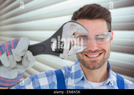 Zusammengesetztes Bild überzeugt Handwerker tragen Schutzbrille Schraubenschlüssel mit gedrückter Stockfoto