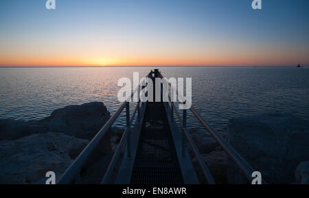 Ein Fischerei-Plattform Extendes heraus über Lake Michigan wie die Sonne den Horizont trifft Stockfoto