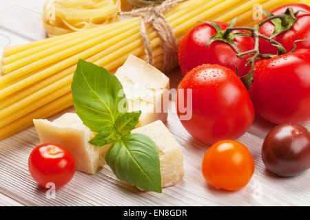Italienische Küche kochen Zutaten. Nudeln, Tomaten, Basilikum auf Holztisch Stockfoto