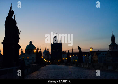 Sonnenaufgang über der Ostturm von der Karlsbrücke entfernt. Statuen in der Silhouette mit den Straßenlaternen aglow Stockfoto