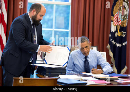 Präsident Barack Obama, unterstützt durch Personal Vizesekretär Ted Chiodo, unterschreibt Rechnungen im Oval Office, 26. September 2014. Stockfoto