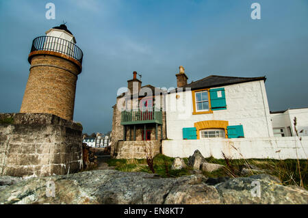 PortPatrick Leuchtturm mit benachbarten Häusern am Hafen, dramatischer Himmel an der Westküste Schottlands entnommen Stockfoto
