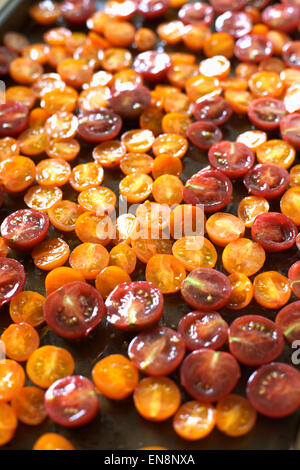 Rote und gelbe Kirschtomaten in zwei Hälften geschnitten und zum Braten vorbereitet. Stockfoto