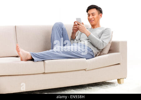 Junger Mann auf dem Sofa sitzen und Musik hören Stockfoto