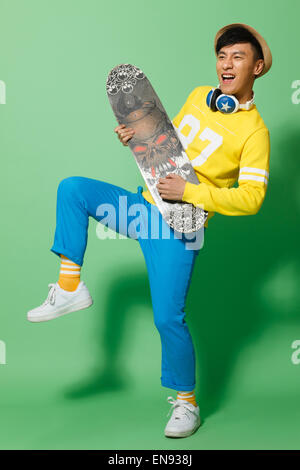 Hübscher junger Mann hält eine skateboard Stockfoto