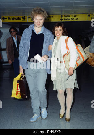 Schauspieler Colin Baker, der Doctor Who in der BBC-Science-Fiction-Programm spielt, fotografiert mit seiner Assistentin Nicola Bryant, Perpugilliam "Peri" Brown am Flughafen Heathrow, spielt vor der Abreise nach einer Convention in Miami. 2. Februar 1984. Stockfoto