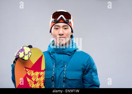 Porträt eines jungen Mannes, ein Snowboard, Blick in die Kamera halten Stockfoto