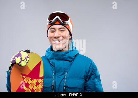 Porträt eines jungen Mannes, ein Snowboard, Blick in die Kamera halten Stockfoto