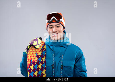 Porträt eines jungen Mannes, ein Snowboard, Blick in die Kamera halten Stockfoto