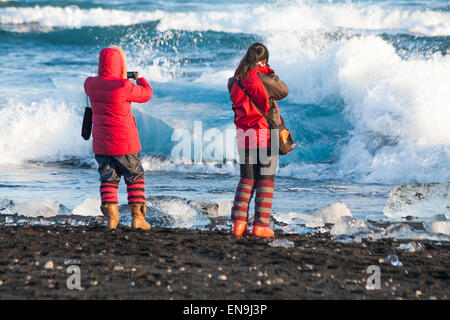 Zwei junge Frauen, die Fotos am Gletschersee Jökulsárlón glazialen Strand, Diamond Beach, Island im Februar Stockfoto