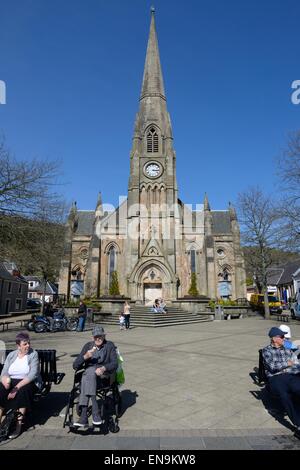 Ein älterer Mann in einem Rollstuhl sitzen essen Eis in der St. Kessog Kirche Platz in Callander, Scotland, UK Stockfoto