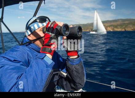 Griechischer Skipper schaut durch ein Fernglas auf seiner Yacht. Stockfoto