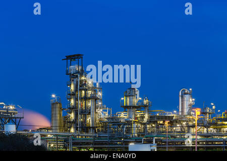 Blick auf die Türme der Destillation einer Chemiefabrik und Raffinerie mit blauen Nachthimmel und Beleuchtung. Stockfoto