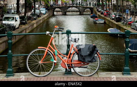Fahrrad angekettet an Geländer auf einer Brücke über einen Kanal in Amsterdam Stockfoto