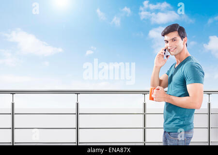 1 indischer Mann Geländer Telefon reden und trinken Tee Stockfoto