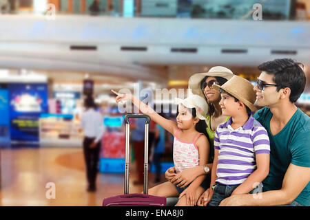 indischer Eltern und Kinder warten Flughafen anzeigen Stockfoto