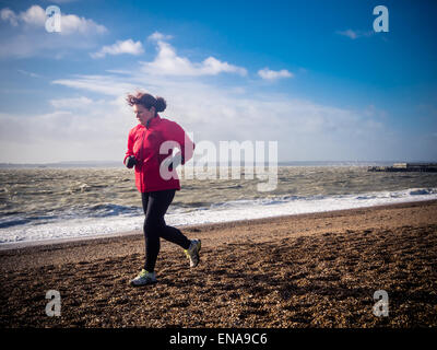 Ein weibliche Läufer läuft entlang Southsea Strand in Portsmouth, Hampshire, England Stockfoto