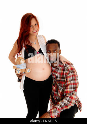 Ein afrikanischer amerikanischer Mann hält sein Ohr auf seine Frau Babybauch, weißen Hintergrund isoliert. Stockfoto