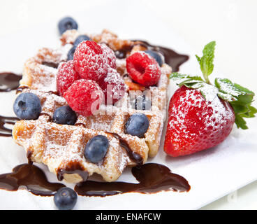 Belgische Waffel mit Puderzucker, Schokolade Sirup und Obst auf weiß Stockfoto