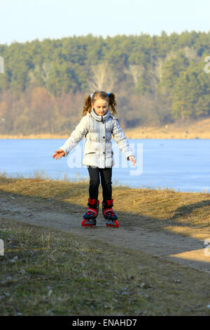 schöne Mädchen geht in Inline Skates auf dem Boden Stockfoto