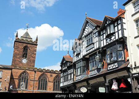 Gebäude und Geschäfte entlang der Bridge Street an der Ecke der Eastgate Street mit St. Peterskirche an der Rückseite, Chester, England. Stockfoto