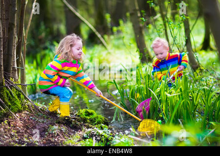 Kinder spielen im Freien. Zwei Vorschüler Kinder fangen Frosch mit bunten Netz. Kleine Jungen und Mädchen in einem Wald Fluss angeln Stockfoto