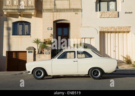 Ford Escort MKI Malta in weiß mit Häusern im Hintergrund. Stockfoto