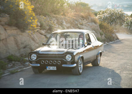 Ford MKI Escort in Malta, schwarzen Auto in Bewegung mit einem natürlichen Sonne Aufflackern Stockfoto